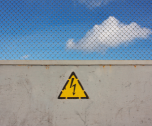 Caution sign on brick wall with sky above to invite companies to publish a toll free number on their website.